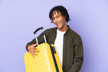 Young african american man isolated on purple background in vacation holding a travel suitcase like a guitar