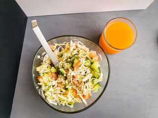 Fresh salad with cucumber, cabbage and tomatoes on a table. Fresh orange juice 