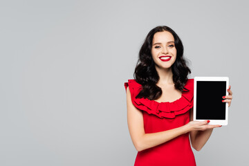 Fototapeta premium cheerful woman with red lips holding digital tablet with blank screen isolated on grey