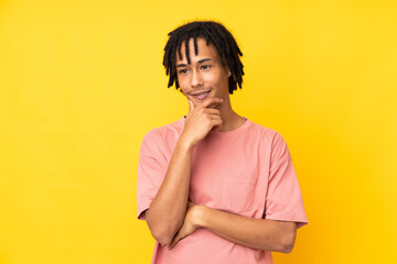 Young african american man isolated on yellow background looking to the side