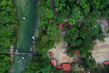 Aerial top view of a bridge over a crystal clear river next to a tropical resort