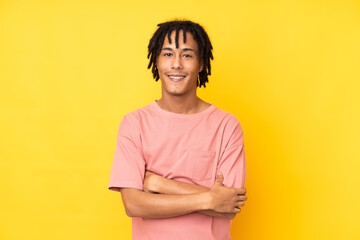 Young african american man isolated on yellow background with arms crossed and looking forward