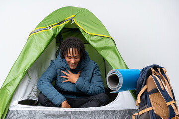 Young african american man inside a camping green tent smiling a lot