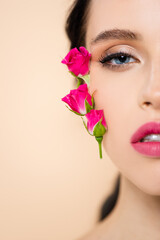 Fototapeta premium cropped view of sensual young woman with flowers on face looking at camera isolated on pink