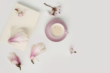 beautiful tender flat still life, card on a beige background, magnolia buds, a cup of cappuccino,...