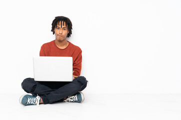 Young african american man sitting on the floor and working with his laptop feeling upset