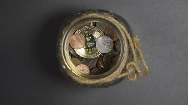 Close-Up of Gold Bitcoin drop in Piggy Bank Jar of Coins with White Background