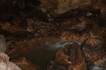 鍾乳洞内部の暗い岩場を流れる水