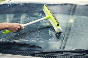 Washing a soapy bronze car with a cloth,car glass wash brush