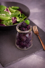 Fototapeta na wymiar Blackberries in jar with salad. Delicious organic food, salad spinach, peas, beets, berries. Vegetarian lunch.