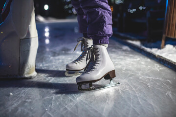 Close up view of new white ice skates boots on rink in motion, girl ice skating on arena, concept of ice skating in winter, holiday christmas time