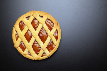 Apricot jam pie on dark background, top view. Flat lay with copy space