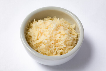 Small ceramic pot with grated cheese. Isolated on white background
