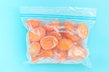 Package with frozen tomatoes on blue background, concept of saving leftovers.