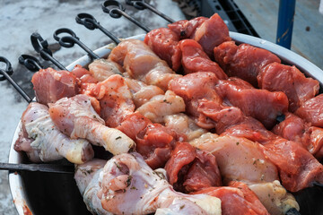 Raw pork skewers and chicken thighs cut into pieces and on skewers closeup