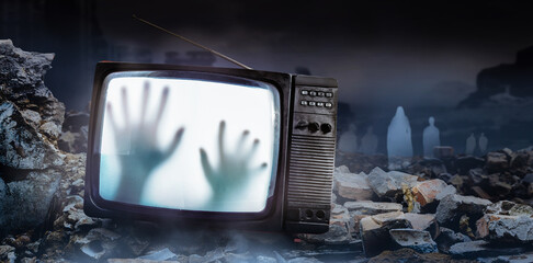 Horror photo of an old black scary haunted tv set with ghost hands on screen, standing on dark...