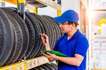 Car Mechanics pose check a quality tire of car wheels in store warehouse for customer in garage...