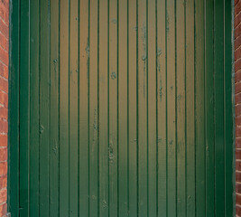 Green wooden wall on  brick building backdrop