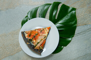 Slice of black dough pizza on plate. Fast food dish on anthracite background. Piece of pizza with...
