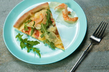 Slice of chicken pizza with ingredients on plate. fork near Fast food dish on anthracite stone background. Piece of seafood pizza with prawns, fresh arugula leaves and sliced Parmesan cheese
