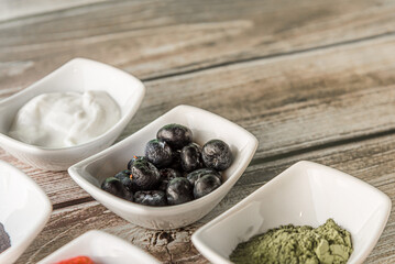 Raspberries, yoghurt, and healthy ingredients in wooden background