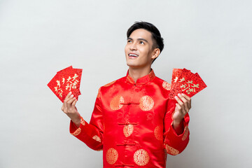 Asian man in traditional oriental costume holding red envelopes or Ang Poa with text mean lucky - wealthy for Chinese new year concepts