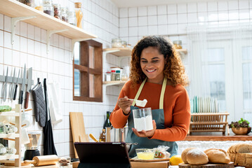 Young Afican American woman learning online  cooking class via tablet computer in kitchen at home