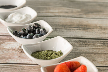 Raspberries, yoghurt, and healthy ingredients in wooden background