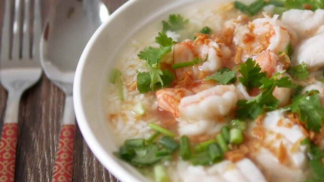 Slow motion panning shot boiled rice soup with fish and shrimp
