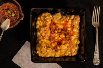 Traditional Argentine stew served in a square black bowl on a black table. Aereal view