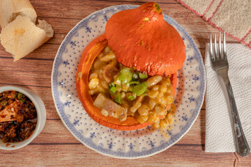 Classic typical food from Argentina and South America, Locro, served in a pumpkin cooked on a vintage plate. Accompanied by the hot sauce. Overhead view