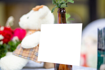 Blank card on the bottle with clipping path. White paper on the table. Empty card valentine concept.