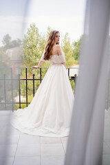 rear view. beautiful young woman in a white wedding dress stands on terrace. 