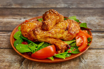 Roasted spicy chicken drumstick with salad on white background.