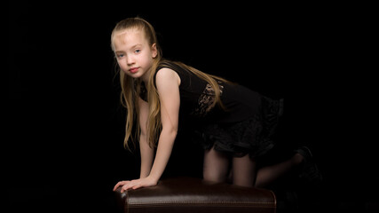 Cute little girl in a dance suit. On a black background.