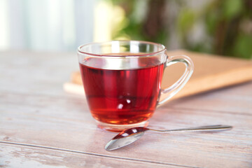 A cup of black tea and a book with a spoon next to it