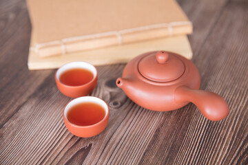 Purple clay pot and two bowls of hot tea and notebook