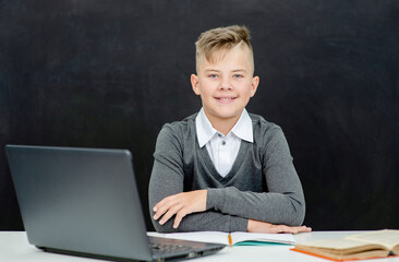 Happy teen boy sits with laptop for education. Distance education concept