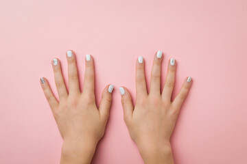 Two women's hands with makeup on a pink background.