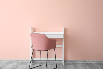 Stylish table and chair near color wall