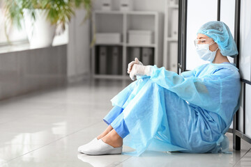 Portrait of depressed female surgeon in clinic
