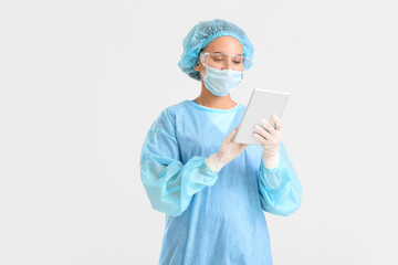 Portrait of female surgeon with tablet computer on light background