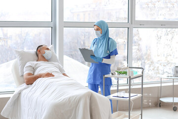 Female Muslim doctor visiting male patient in clinic