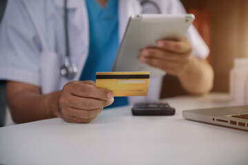 Doctor use credit cards to conduct financial transactions through phones, tablet, and laptop in the morning. 