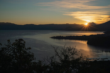 Sunrise on Lake Atitlán the sun rising behind the mountains and volcanoes - first rays of sun on beautiful Lake in Sololá Guatemala