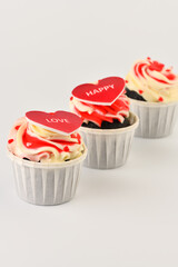 Cupcakes. Cupcakes in the shape of a heart in white cups with inscriptions on a gray background. Valentine's Day. Vertical photo