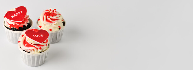 Cupcakes. Cupcakes in the shape of a heart in white cups with inscriptions: love,  happy on a gray background. Valentine's Day banner for bakery, confectionery. Copy space