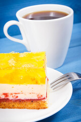 Creamy sweet sponge cake with different layers and jelly. Cup of coffee. Dessert for celebrations