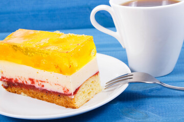 Creamy sweet sponge cake with different layers and jelly. Cup of coffee. Dessert for celebrations