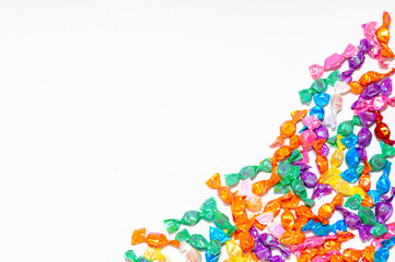 In the lower corner of the white background, small candies in multi-colored wrappers are laid out....